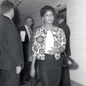 African-American woman with purse in hallway with three white men in suits