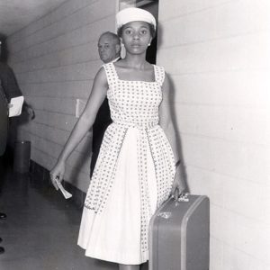 African-American woman in dress with bags in hallway