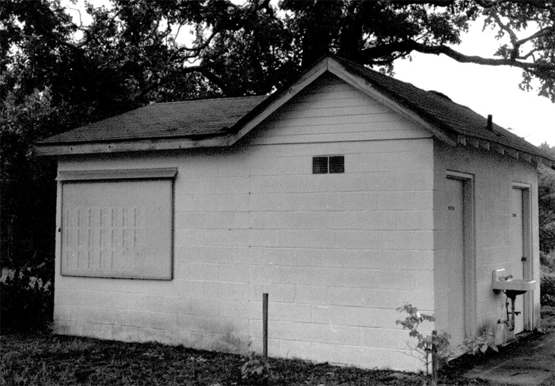 Side view of single-story bathroom building with water fountain