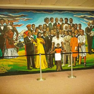 Mural depicting African-American historical figures on museum wall with stanchions