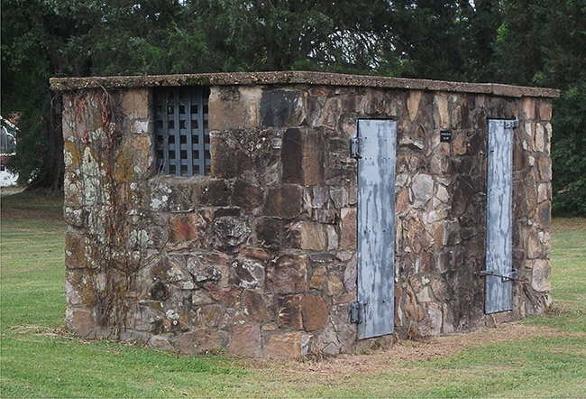Small stone building with two metal doors and barred window