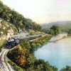 Steam locomotive with cars rounding a curve near a river
