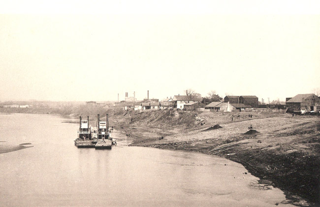 Pair of steamboats socked on river with town buildings in the background