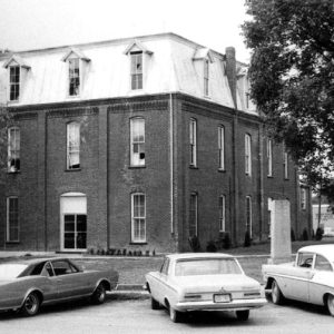 Three-story building with parked cars and trees
