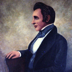 Profile view of white man in suit with a blue striped cravat