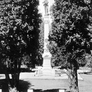 Soldier on tall obelisk shaped monument between two trees