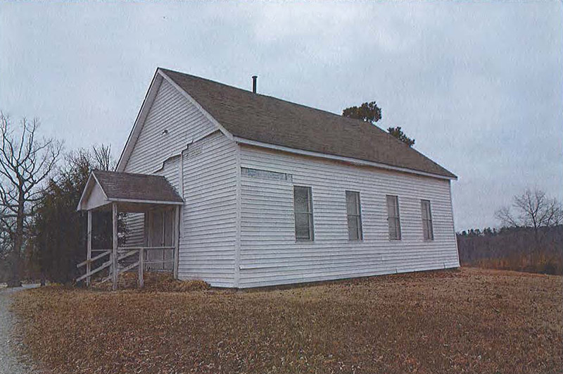 Side view of single-story building with wood siding and covered entrance