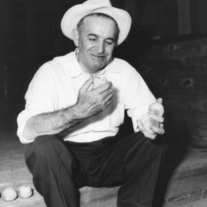White man in hat sitting on step and holding a peach
