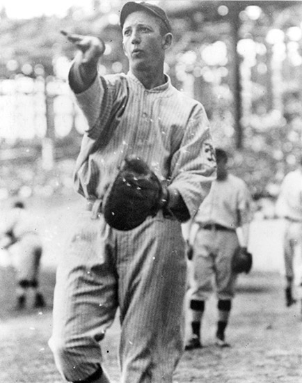White man in uniform with glove throwing a pitch