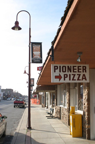 "Pioneer Pizza" sign on storefront with curved street lamp and parked cars