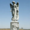 Angel statue on engraved grave monument in field