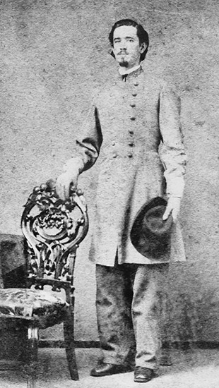 White man standing in gray military uniform with chair and hat
