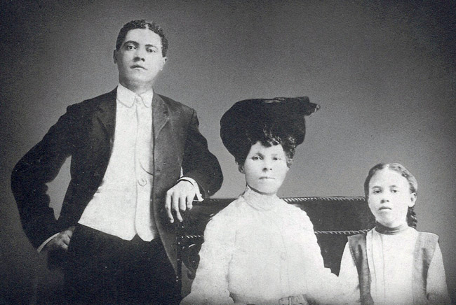 African-American man, woman, and son posing together in formal dress