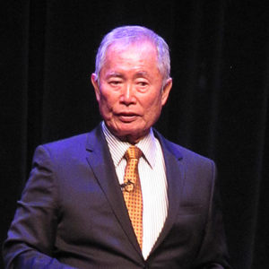 Asian-American man in suit and tie on stage