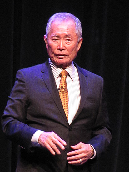 Asian-American man in suit and tie on stage