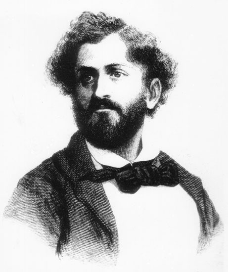 White man with curly hair and beard in suit and bow tie