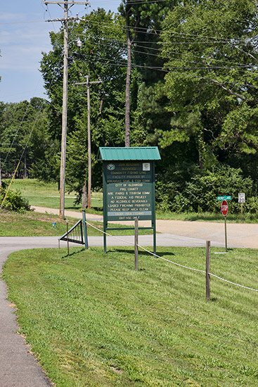 Green park sign and fence at rural intersection