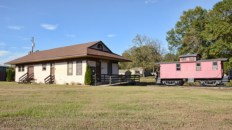 Railroad depot building with wheelchair ramp and red train car