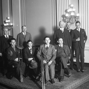 Group of white men standing and disabled white children seated