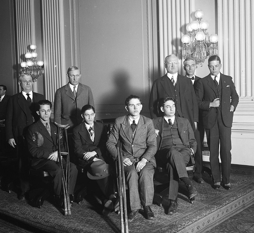 Group of white men standing and disabled white children seated