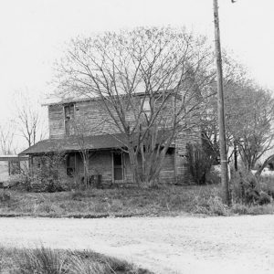 Two-story house and telephone pole on dirt road