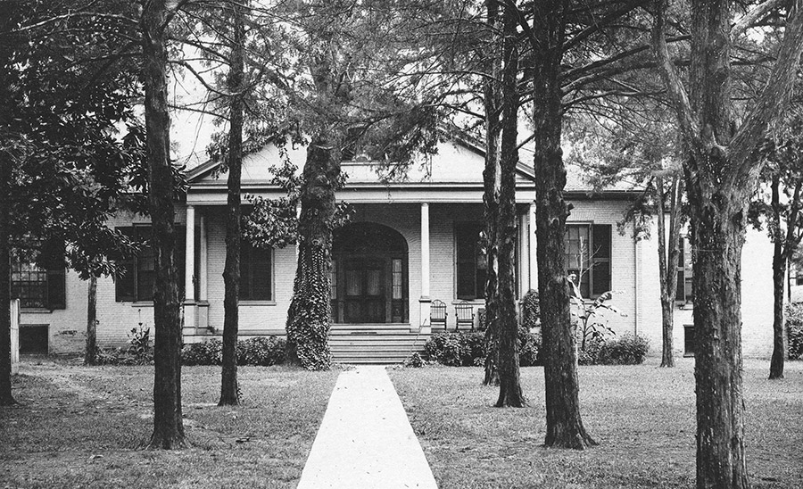 Single-story house with covered porch with trees in front yard