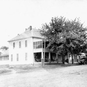Two-story hotel building with tree on dirt road with storefronts