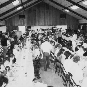 Men and women eating at long tables in school cafeteria
