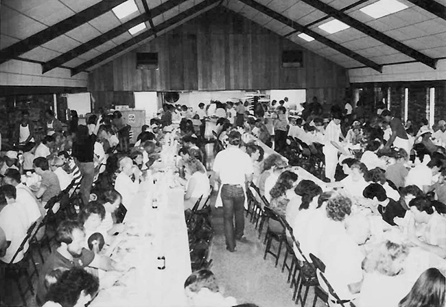 Men and women eating at long tables in school cafeteria