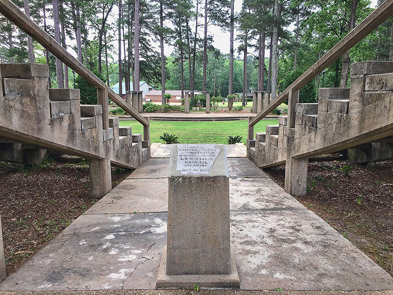 Looking between concrete stands in outdoor auditorium and plaque on college campus