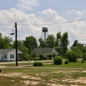 Single-story houses on road with water tower in the background
