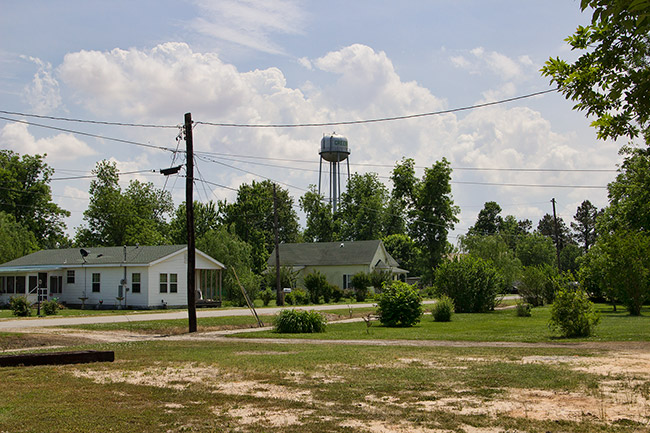 Single-story houses on road with water tower in the background