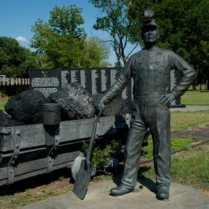 Statue of miner with mine cart loaded with coal
