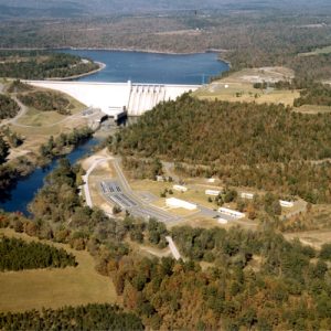 Aerial view of lake and concrete dam with trees and countryside in the background