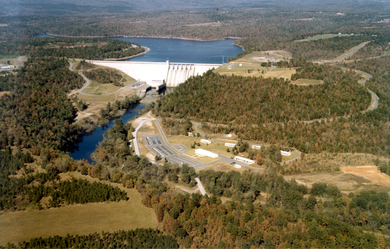 Aerial view of lake and concrete dam with trees and countryside in the background
