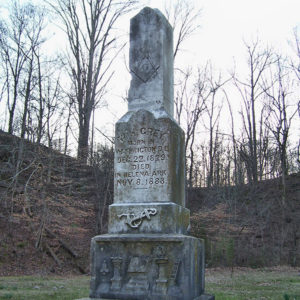 Weathered grave monument with engraving on pedestal and Masonic symbol on top