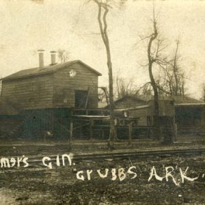 Gin building and outbuildings with bare trees and railroad