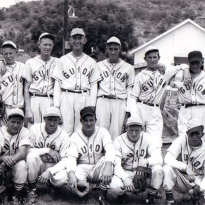 Group of white men posing in "Guion" uniforms with caps and mitts