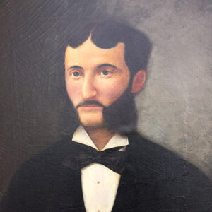 White man with mustache and sideburns in suit and bow tie