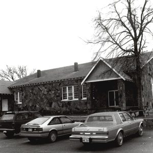 Cars parked in front of stone building with covered entrances