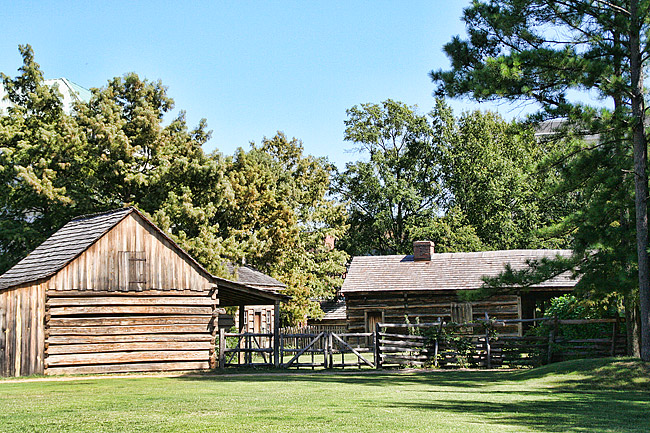 two log cabins facing each other across fenced-in yard