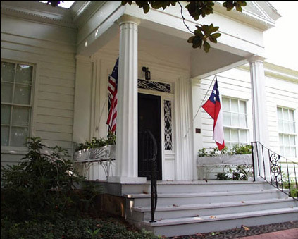 Wood frame home classical front porch American flag left and Confederate national flag Stars and Bars right