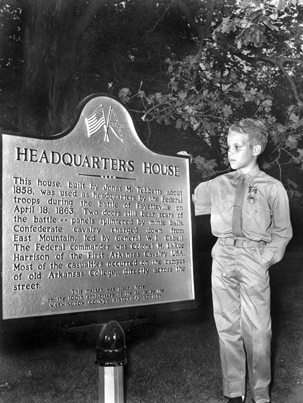White boy standing next to commemorative plaque