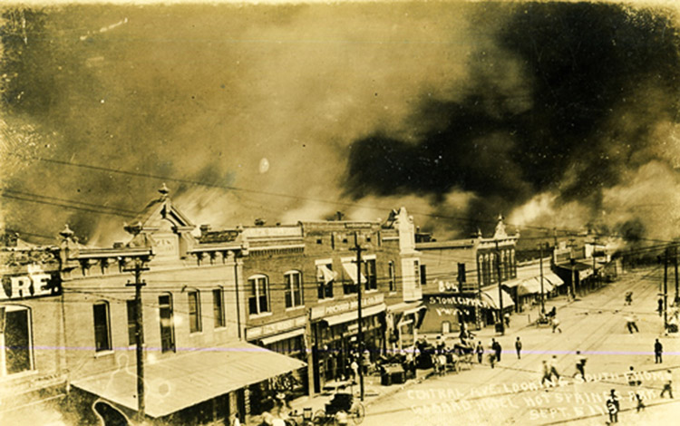 Burning brick buildings on street with smoke filling the sky