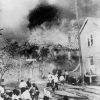 Crowd of people watching a multistory house burn down