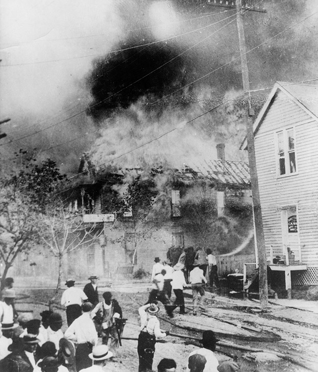 Crowd of people watching a multistory house burn down