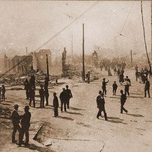 Crowd of people on city street observing destroyed buildings