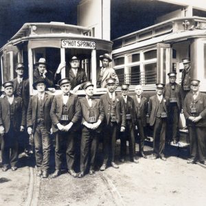Group of white men in uniforms posing with trolley cars