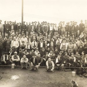 Group of men seated and standing in rows outdoors