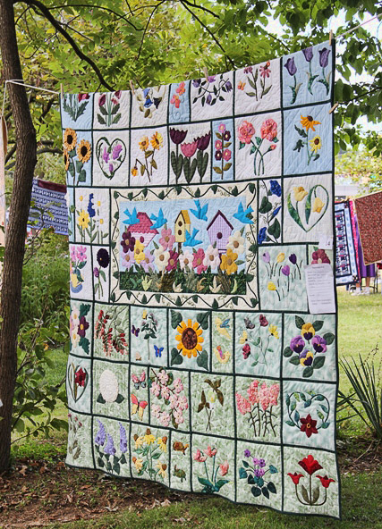 Large floral quilt hanging between two trees